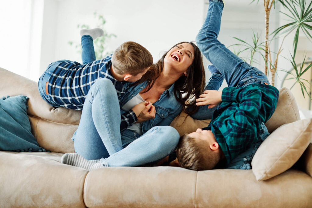 Woman laughing with kids on a couch.