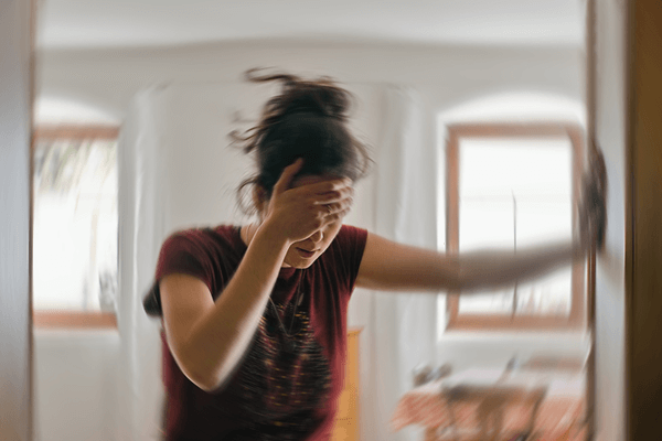 Woman leaning against a wall from dizziness.